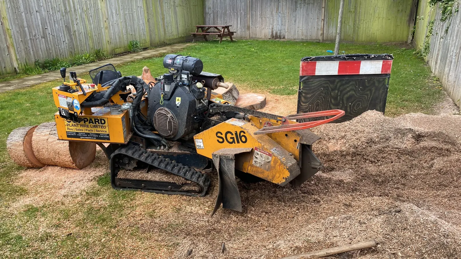 Tracked stump grinder positioned on a lawn ready to grind out a tree stump