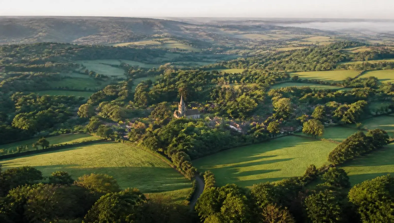 Rolling wooded countryside, hedgerows and village rooftops typical of the landscape around Oxted